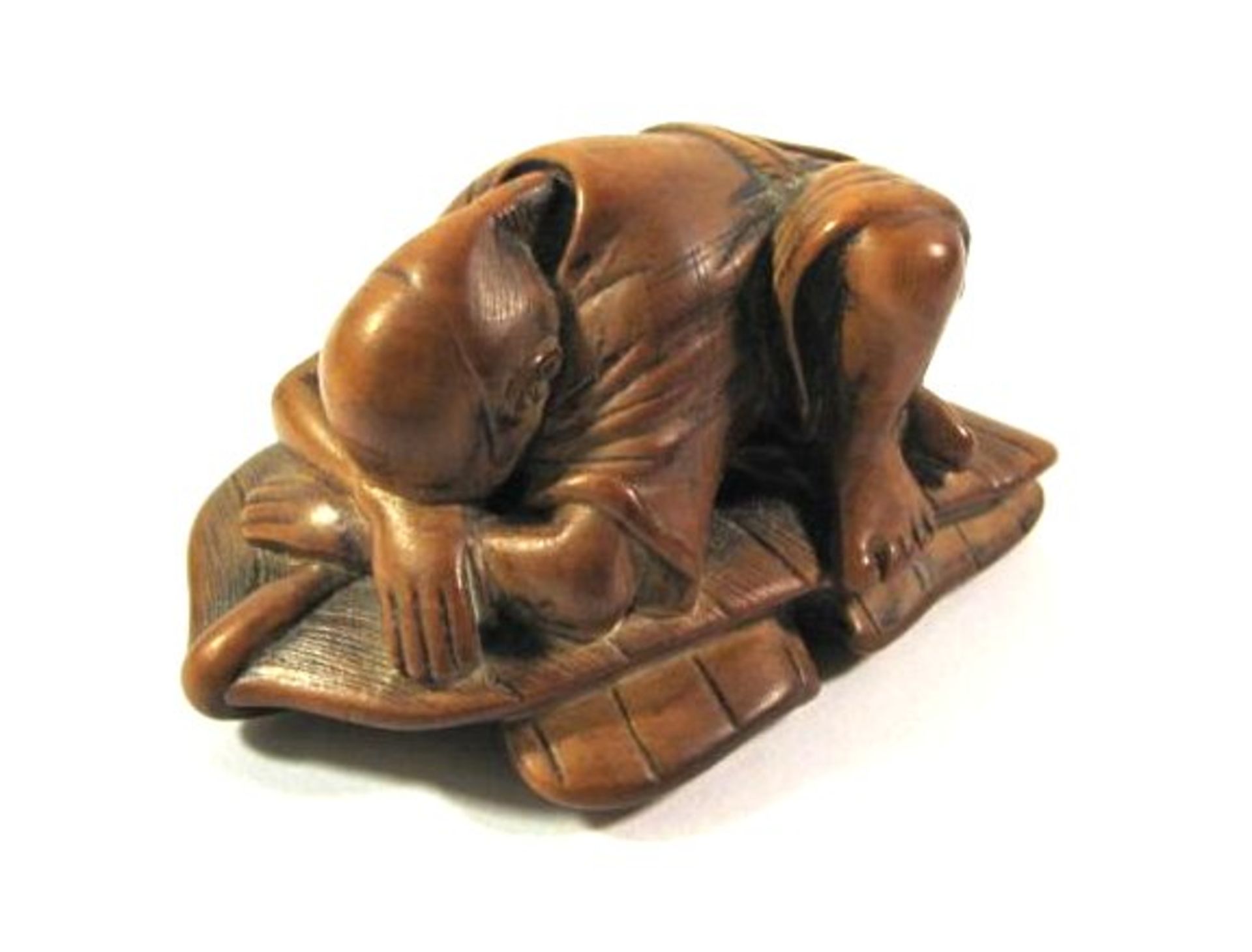 Netsuke, Japan, rotbraunes Holz, Darstellung eines schlafenden Mannes auf Palmenblättern, wohl 19.