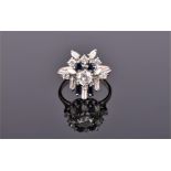 A white metal, diamond, and sapphire cluster ring of geometric design, set with round cut central