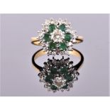 An 18 carat yellow gold, diamond, and emerald floral cluster ring centred with round cut diamond