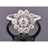 An 18 carat white gold and diamond snowflake cluster ring set with raised central stone of 0.65