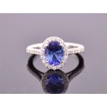 An 18 carat white gold, diamond, and tanzanite halo ring, set oval cut tanzanite of approx. 2.0