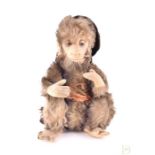 An early 20th century toy monkey, possibly Steiff with jointed arms and glass eyes, a cigarette in