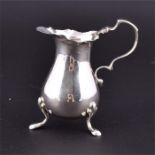 A George IV silver cream jug with shaped rim, plain baluster body supported on three feet. H: 9cm