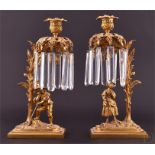 A pair of Regency ormolu figural lustre candlesticks with hanging prism drops suspended from