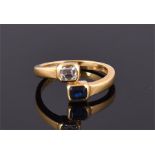 An 18 carat yellow gold, diamond, and sapphire crossover ring set emerald cut sapphire and emerald