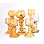 A collection of eight assorted Bohemian hock glasses in green and amber coloured glass with engraved