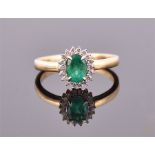 An 18 carat yellow gold, diamond, and emerald cluster ring, having oval cut emerald of approx. 1.0