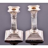 A pair of Victorian silver Corinthian column candlesticks with fluted stems and square stepped
