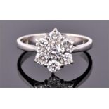 An 18 carat white gold and diamond floral cluster ring set with seven round cut stones of approx.