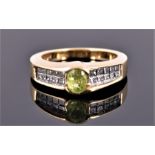 A 14 carat yellow gold, diamond, and peridot ring with central oval cut peridot, the shoulders set