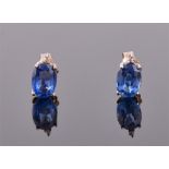 A pair of white metal and blue sapphire ear studs each set with an oval cut sapphire surmounted with