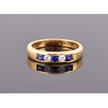 An 18ct yellow gold, diamond and sapphire ring channel-set with three blue sapphires and two round