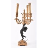An early 20th century gilded cast iron cherub candelabra with cherub as stem balancing on one foot