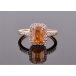A 9ct yellow gold, diamond and sphalerite ring set with an emerald cut orange sphalerite, the