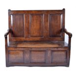A George III oak settle of small proportions the panelled back set above a hinged box seat flanked