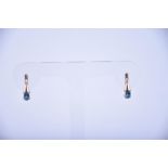A pair of 14ct rose gold and blue topaz earrings the semi-rounded mounts each set with an oval cut