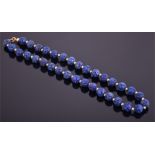 A 9ct yellow gold and lapis lazuli necklace comprising thirty three carved beads, of approximately