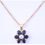 An 18ct yellow gold, diamond, and sapphire floral cluster pendant centred with a round cut diamond