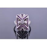 An 18ct white gold, diamond, and ruby Art Deco style ring centred with a round cut diamond, the