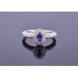 An 18ct white gold, diamond, and sapphire cluster ring set with an oval cut blue sapphire within