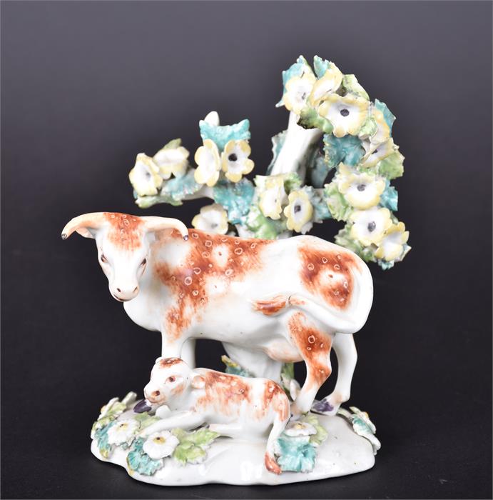 A Derby porcelain cow and calf resting before a flowering tree on an oval grassy base applied with