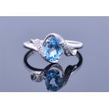A 9ct white gold and blue topaz crossover ring set with an oval cut topaz, the mount set with