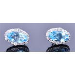 A pair of white metal, diamond, and blue topaz cluster earrings of oval form, each set with a