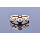 An 18ct yellow gold and diamond ring with bezel set round cut central diamond, flanked by two
