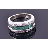 A silver, diamond, and green emerald ring the half eternity mount channel set with four oval cut
