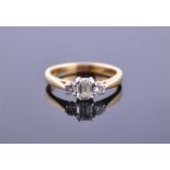 An 18ct yellow gold and three stone diamond ring set with an emerald cut diamond flanked by two