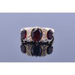 An 18ct yellow gold, diamond and garnet ring the central oval cut garnet half collet set flanked