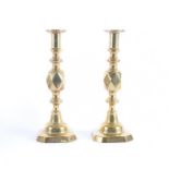 A pair of brass candlesticks the turned stems with faceted central knop decoration, on square