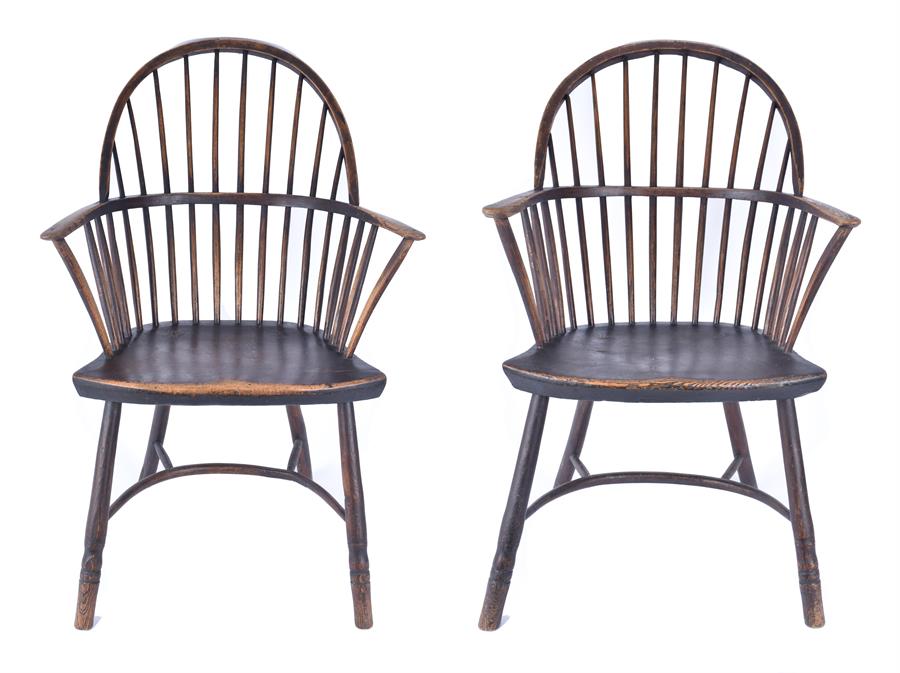 A pair of closely matching Georgian oak Windsor chairs with stick backs and open arms, with solid