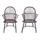 A pair of closely matching Georgian oak Windsor chairs with stick backs and open arms, with solid