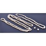 An opera length pearl necklace with white metal, diamond, and sapphire clasp together with a shorter