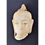 An Indian alabaster Buddha head fragment  with serene expression, lengthened earlobes and topknot,