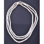 A three-strand freshwater pearl necklace with magnetic white metal clasp.
