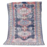 An old Eastern wool rug The red ground decorated with geometric medallions in shades of red and
