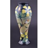 A large Moorcroft Hypericum baluster vase decorated with tubelined flowers on a tan and blue