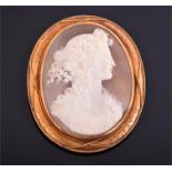 A yellow metal mounted cameo brooch depicting a Classical maiden with flowers in her hair, within an