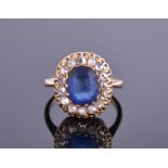A yellow metal, diamond, and synthetic sapphire cluster ring centred with an oval cut blue stone