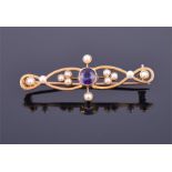 An Edwardian 15ct yellow gold, amethyst, and seed pearl bar brooch  with round cut central amethyst,