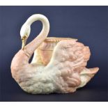 A Royal Worcester blush ivory vase in the form of a seated swan cradling a tapering cylindrical vase