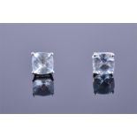 A pair of 14ct white gold and aquamarine earrings each set with a cushion cut faceted stone.