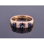 An 18ct yellow gold, diamond, and sapphire ring set with three old cut sapphires interspersed with
