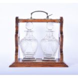 An early 20th Century two decanter tantalus the locking oak frame with silver plated mounts and