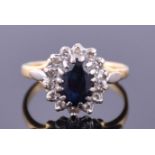 An 18ct yellow gold, diamond, and sapphire cluster ring set with an oval sapphire, size M 1/2 weight