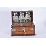 A large early 20th century oak cased three bottle tantalus brass bound with a handle at each side,