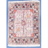 A Persian woollen rug the central cream ground field decorated with birds, animals and flowers,