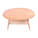 A light Ercol coffee table the oval elm top supported on tapering cylindrical legs with a spindle